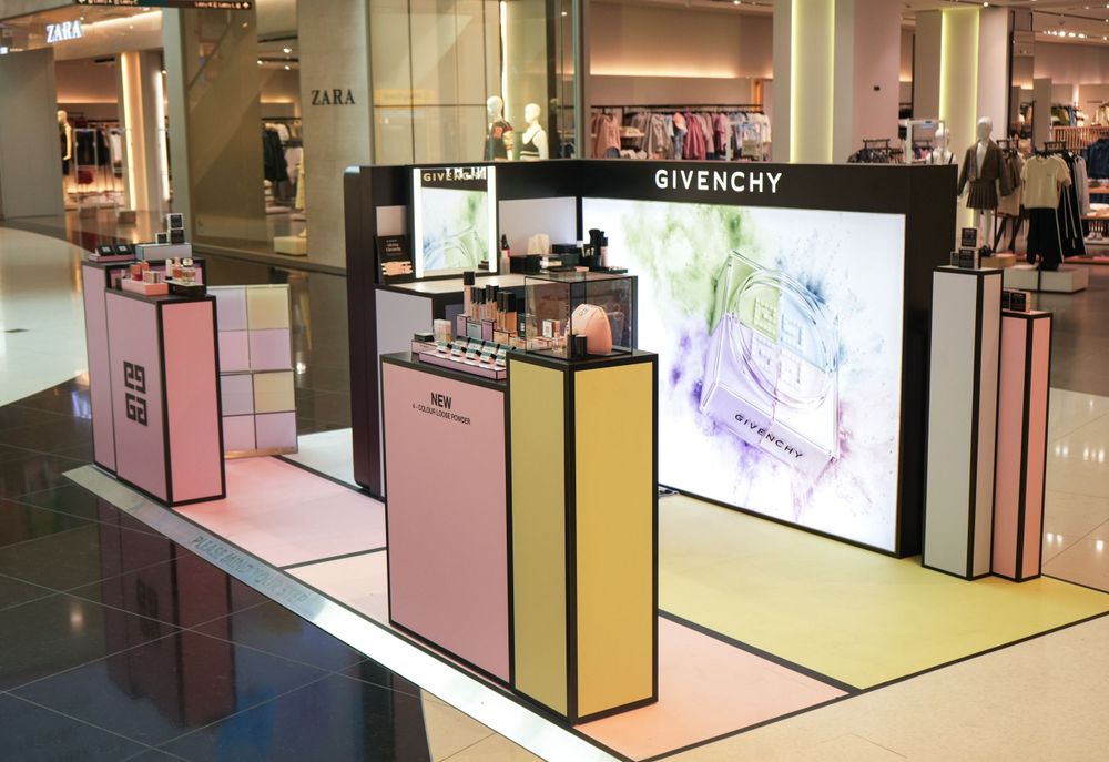 Givenchy beauty counter display with pink and black modular units and digital screen.
