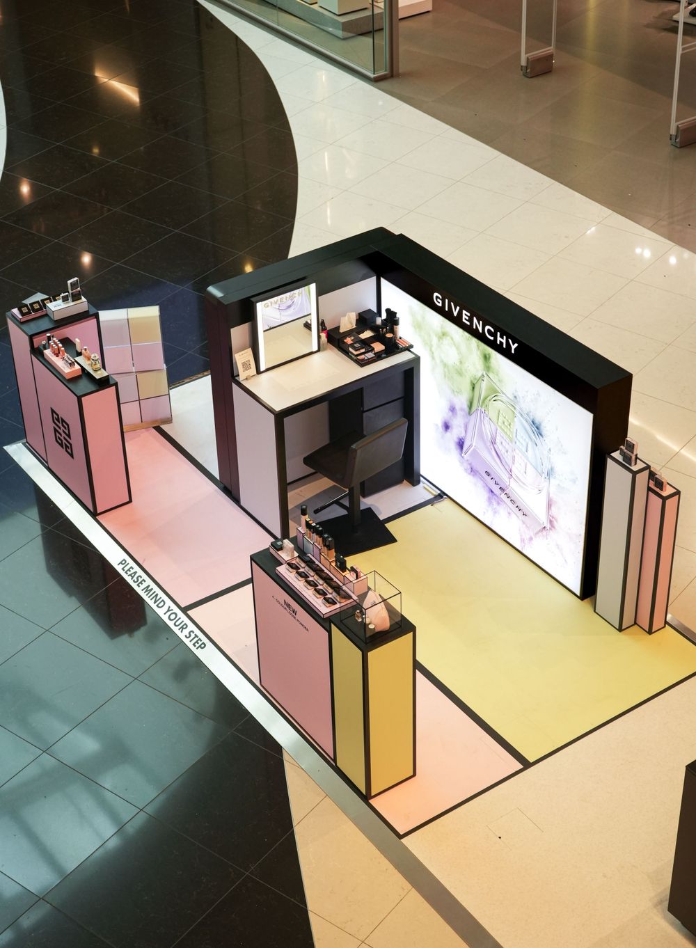 Luxury cosmetics retail display featuring pink and yellow platforms with digital screens.