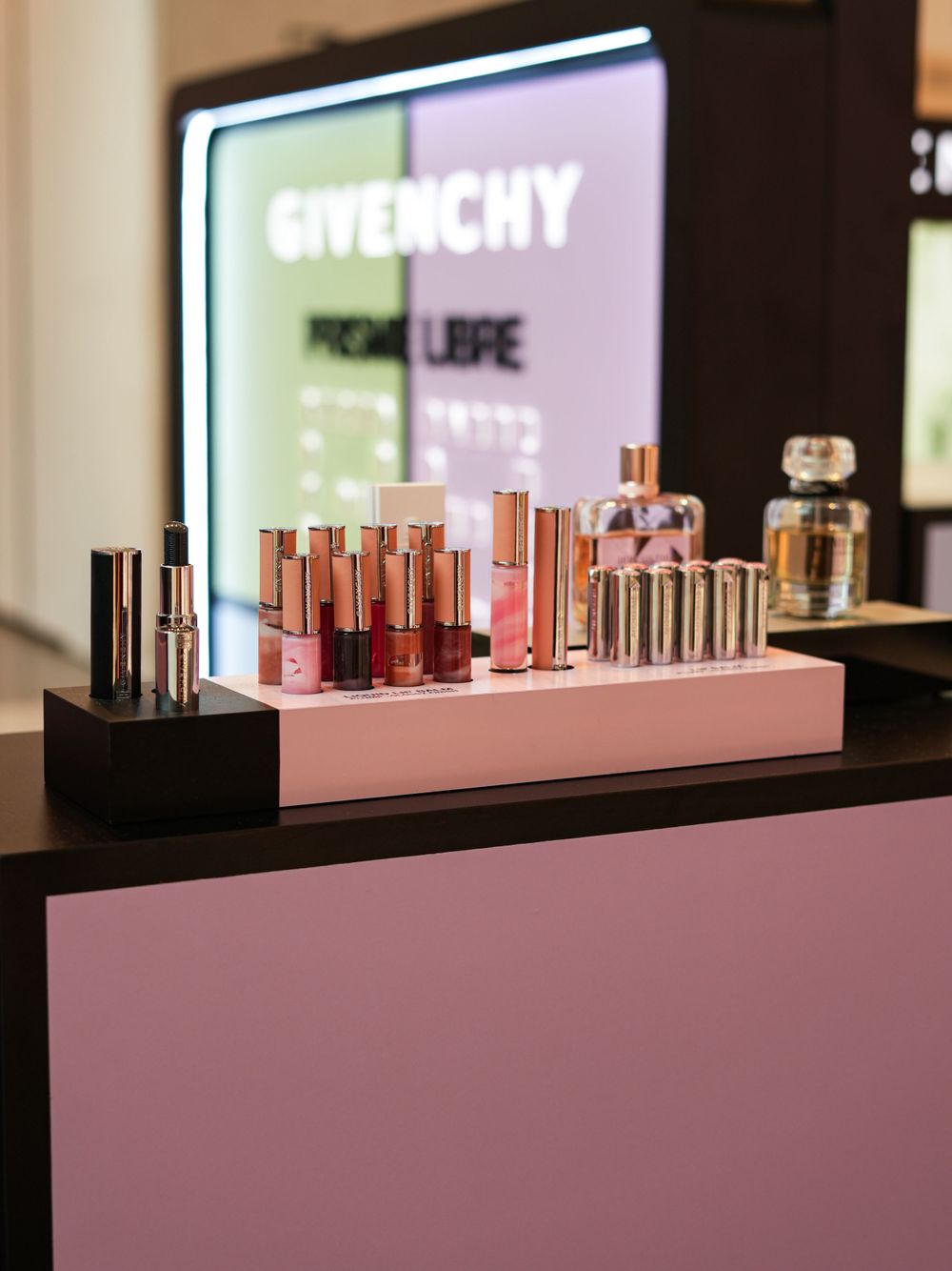 Pink and black Givenchy beauty display showcasing lip products and fragrances.
