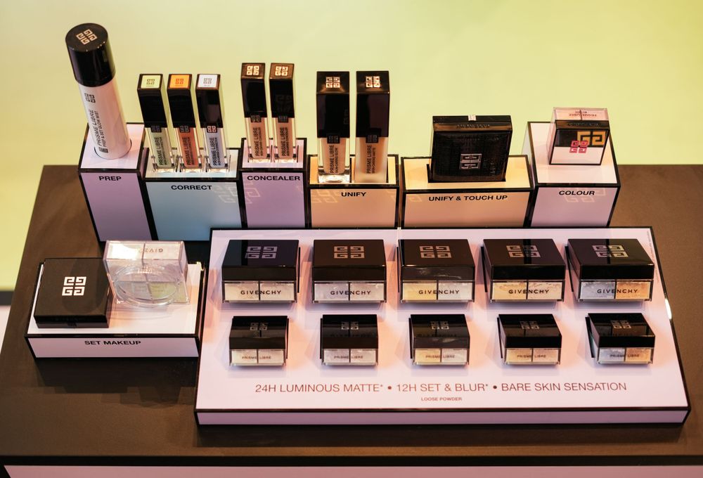 Organized display of Givenchy makeup products on black and pink retail fixtures.