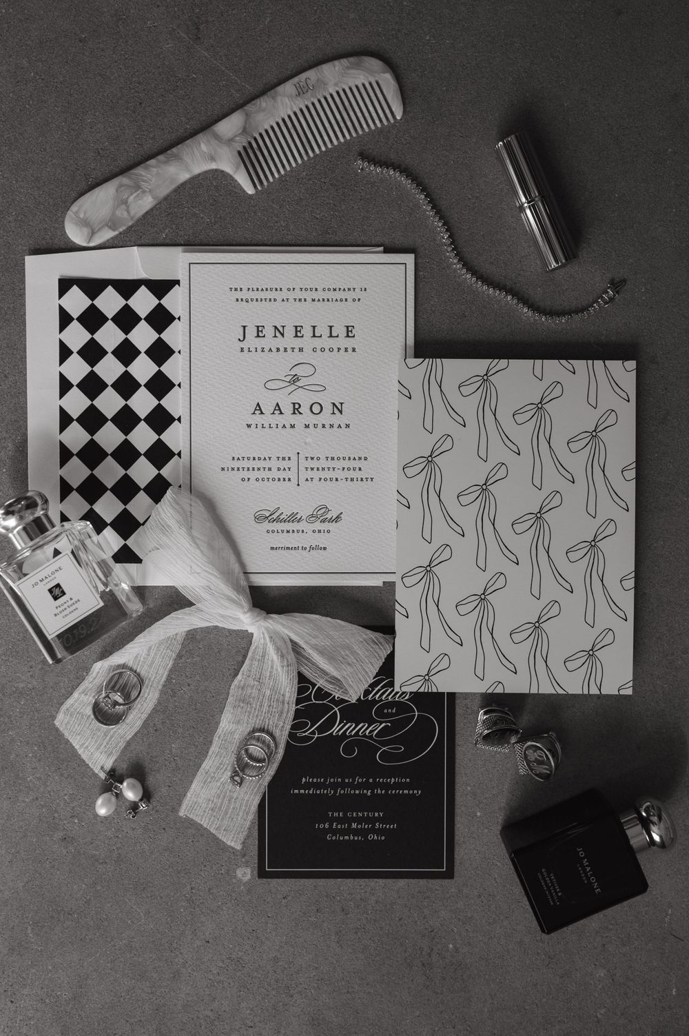 Black and white flat lay of wedding stationery featuring geometric patterns and personal care items.