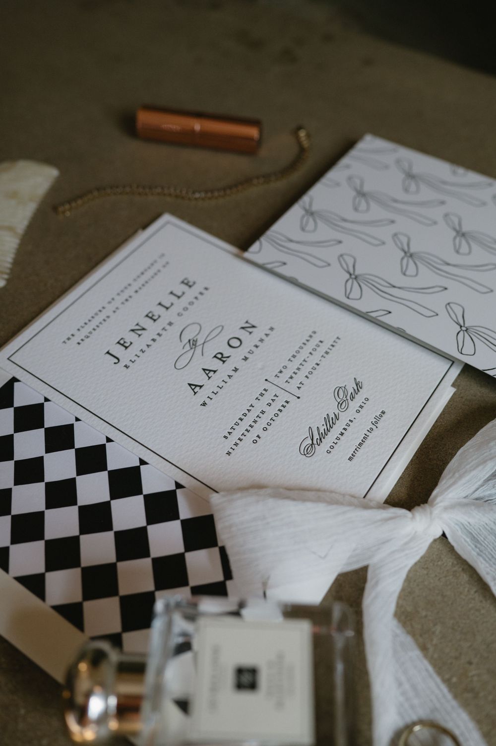 Wedding invitation with checkerboard pattern and elegant typography displayed with decorative elements.