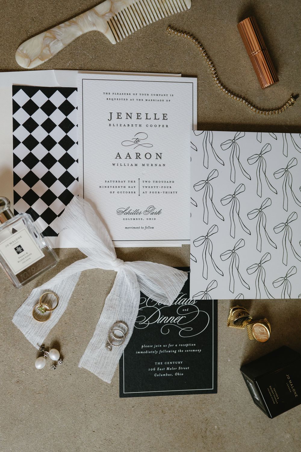 Wedding stationery flat lay featuring geometric patterns and personal items on grey background.