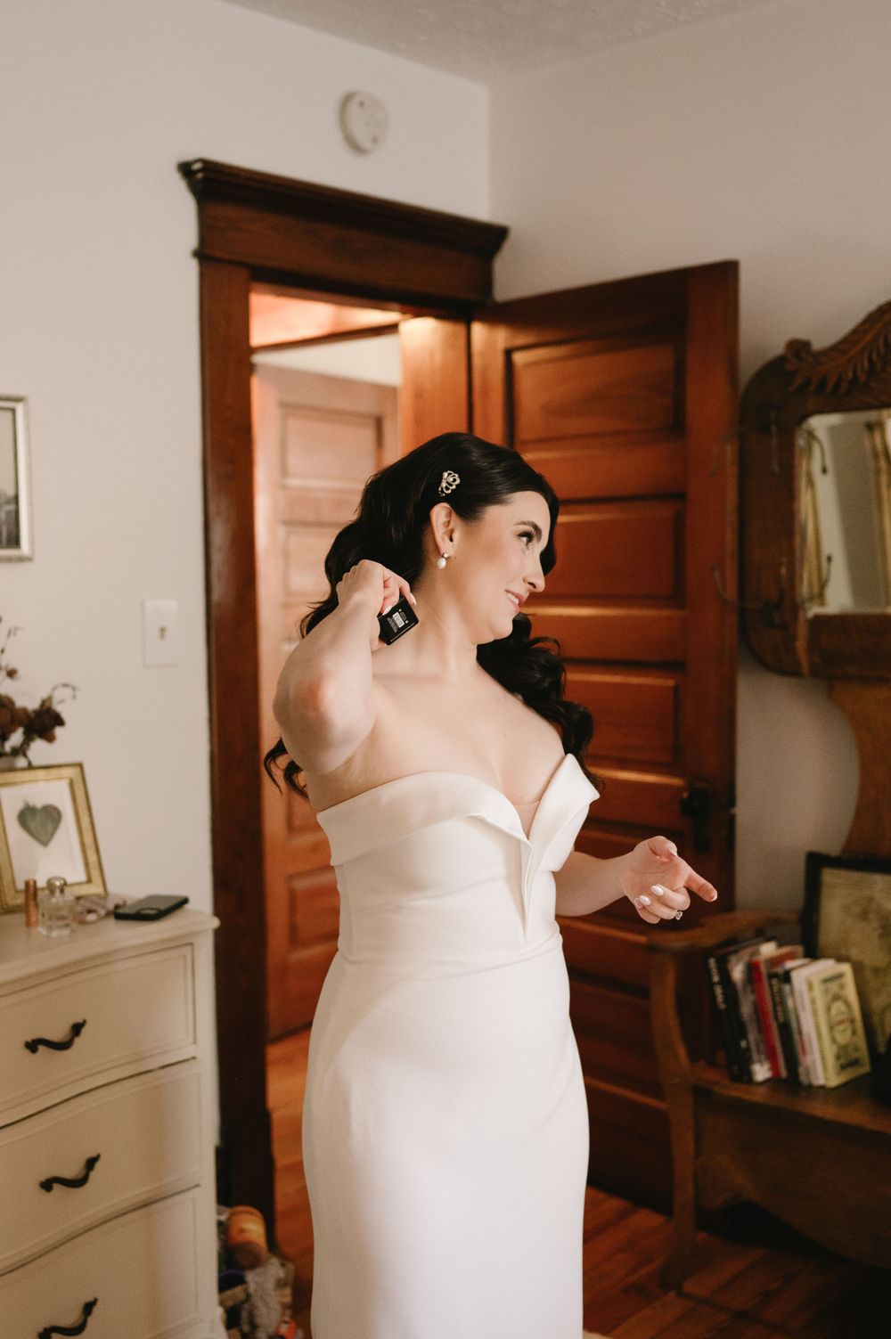 Elegant white wedding dress displayed in a room with wooden doors and vintage furniture.