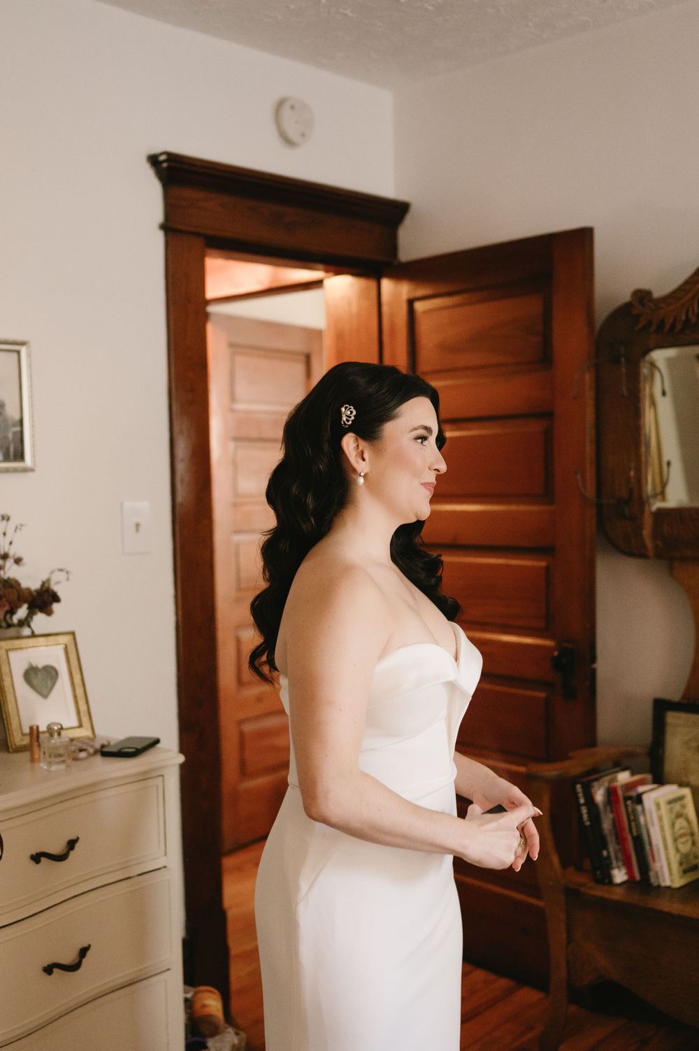 Elegant bridal portrait in a fitted white dress against vintage furniture.