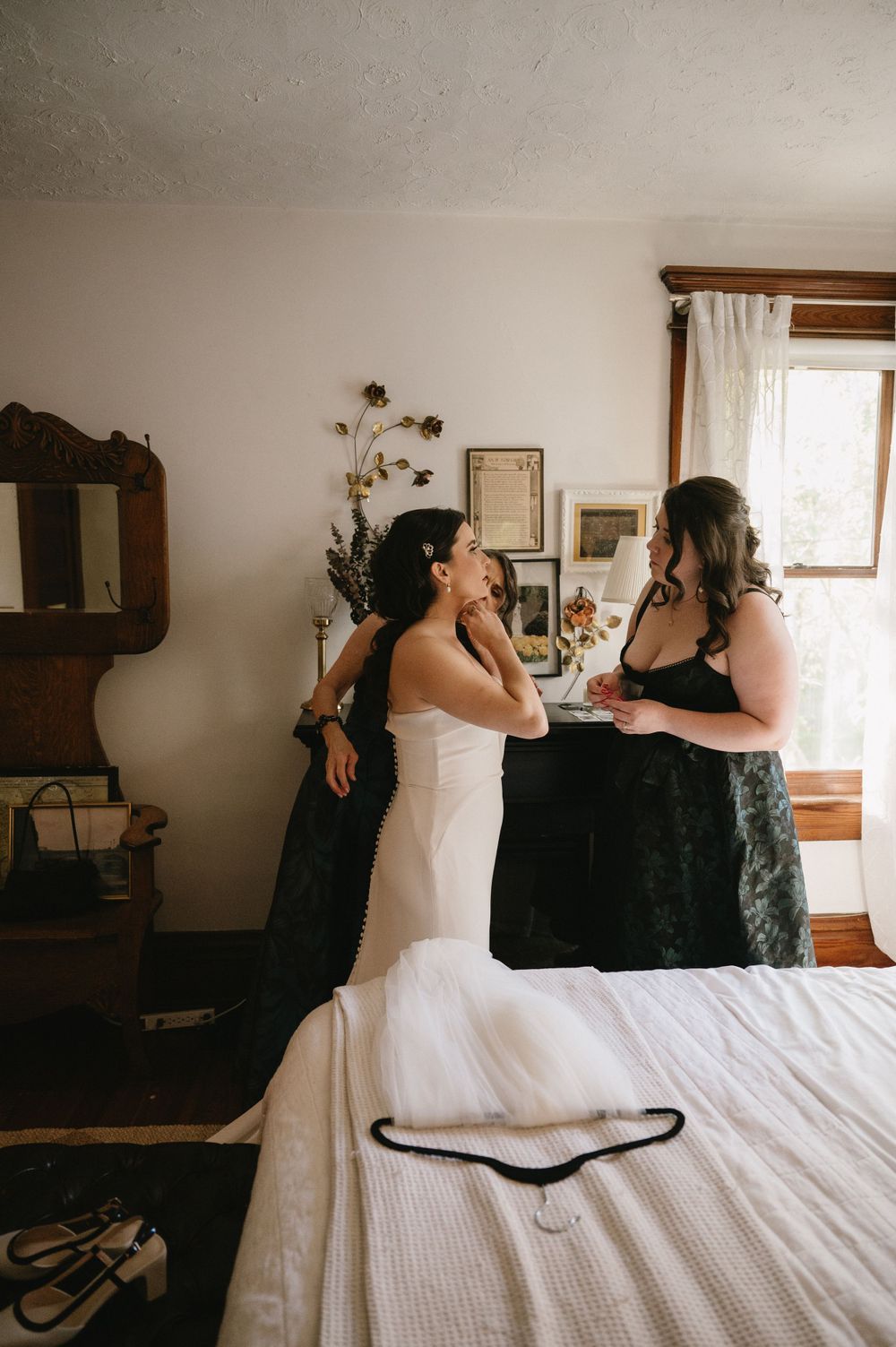 Intimate getting ready moment captured in rustic bedroom with antique furniture.