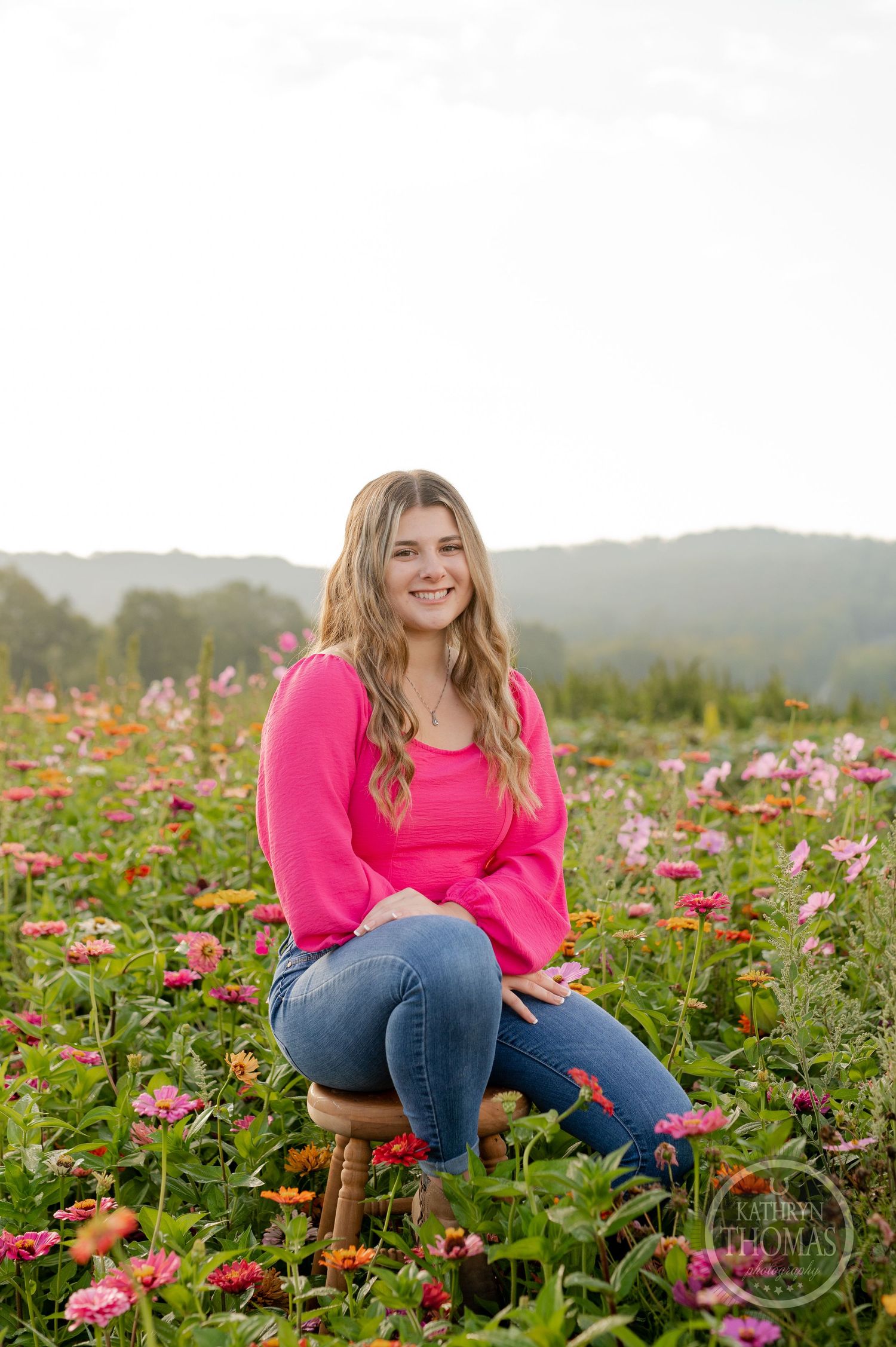 Natural light portrait in a flower field wearing a pink sweater and casual denim.