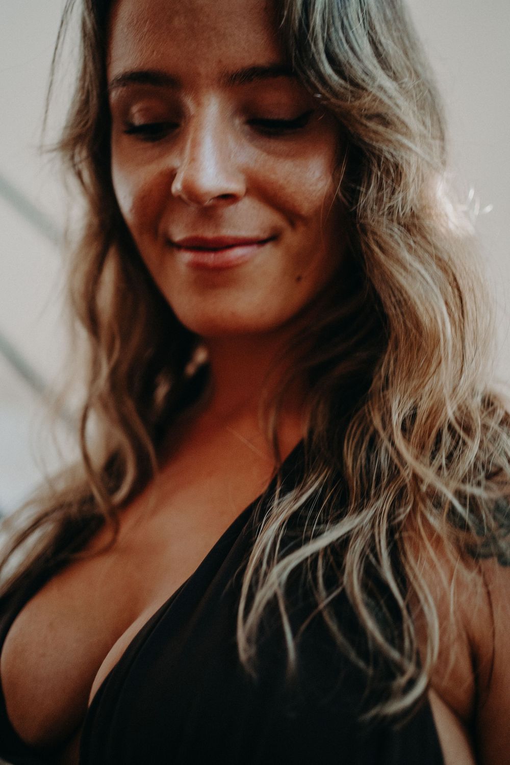 A series of moody portraits showing a woman with wavy hair smiling and looking down in warm lighting.