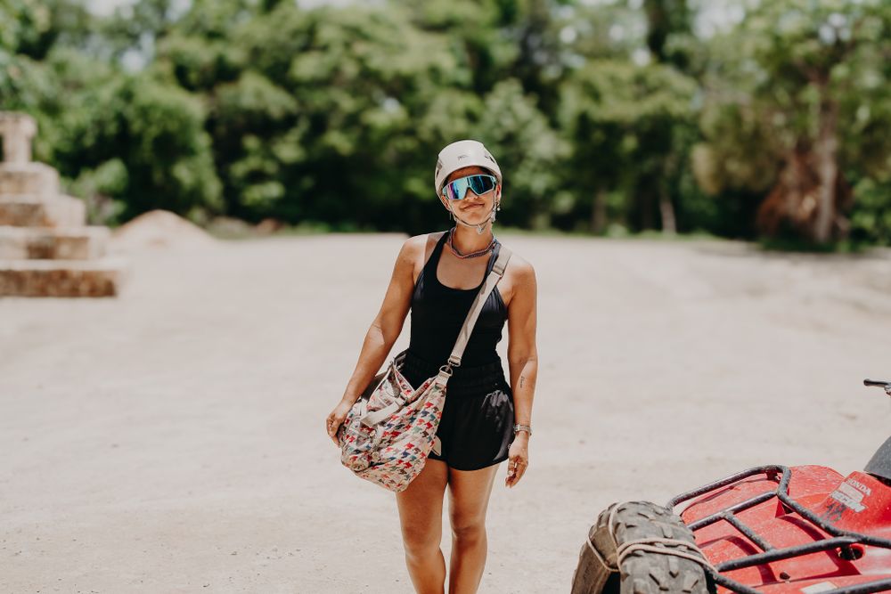 Adventure traveler in athletic wear with bag standing near ATV photoshoot in Puerto Morelos.