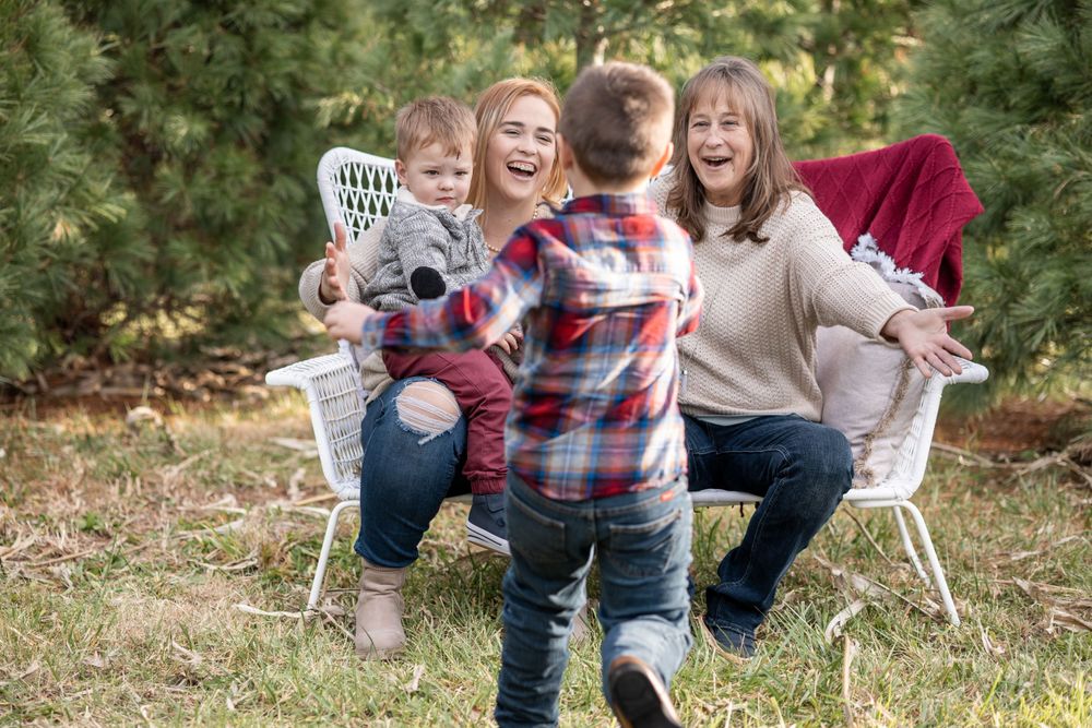Kid runs to brother, mom and grandma sitting on a bench outdoors