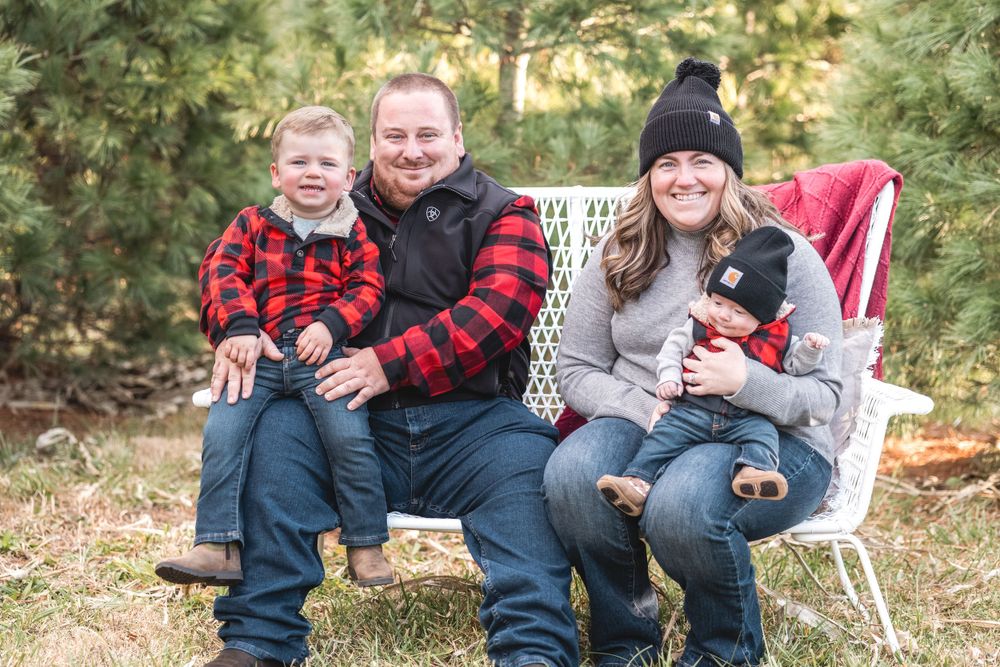 Family of four pose while sitting on a white bench outside