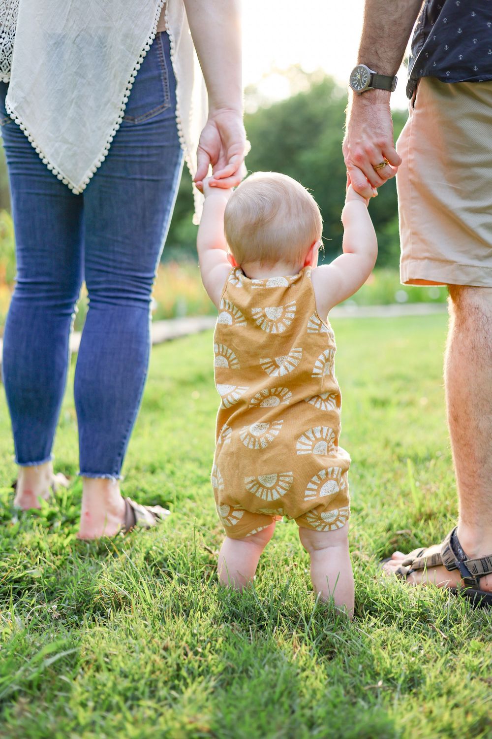 Springfield, IL family photographer captures a toddler walking while holding his parent's hands during a session in Central, IL
