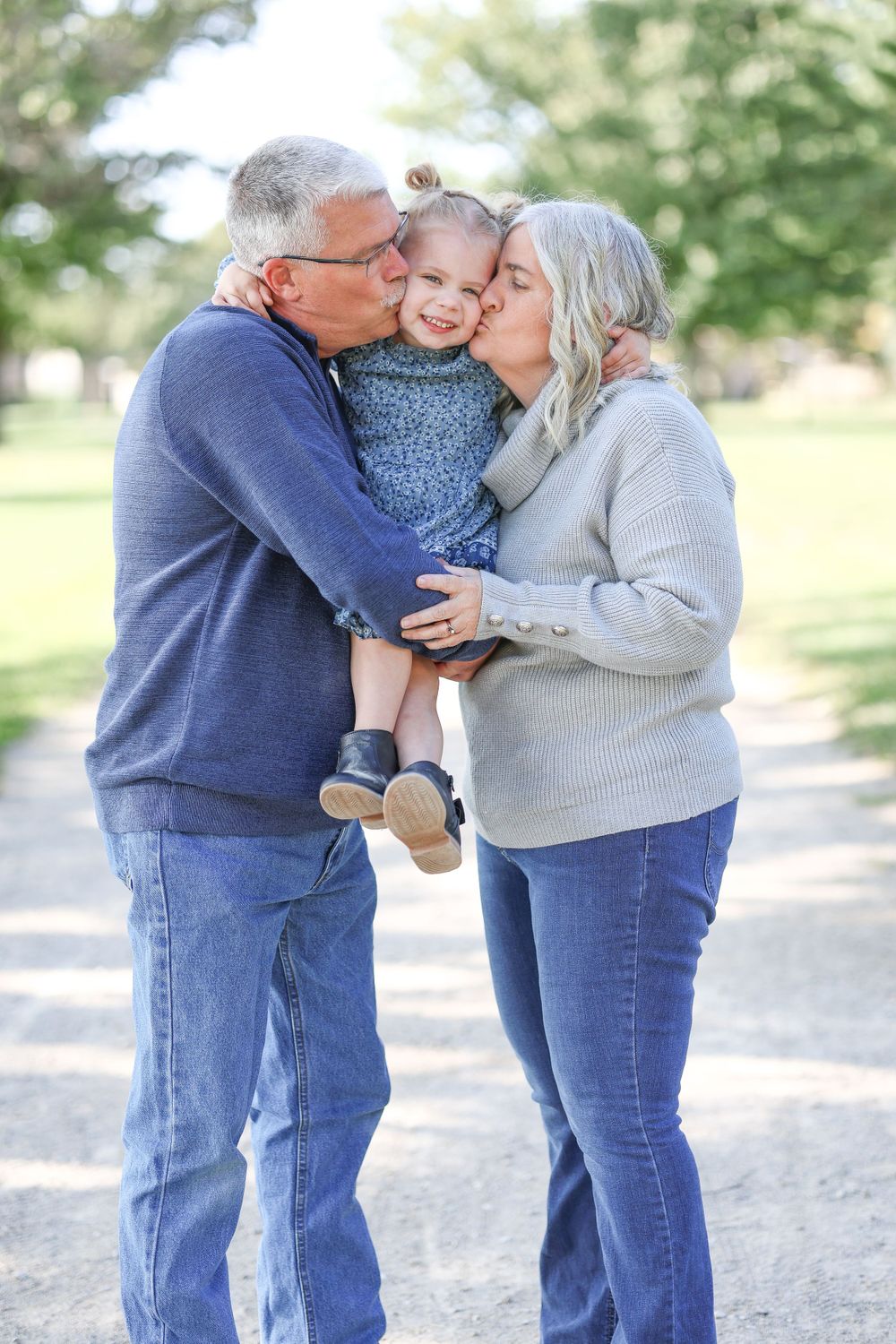 Springfield, IL family photographer captures grandparents kissing their granddaughter's cheeks during a session in Central, IL