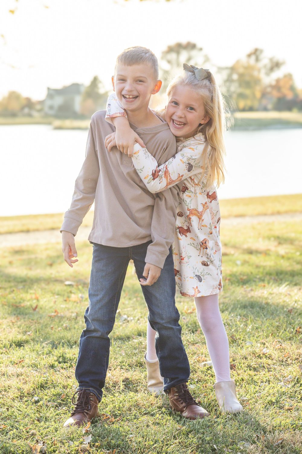 Siblings hug and laugh together in front of a lake