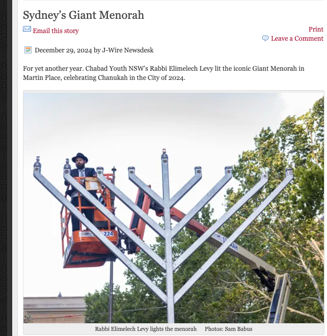 A large metal menorah structure being assembled outdoors with a lift and workers in Sydney.