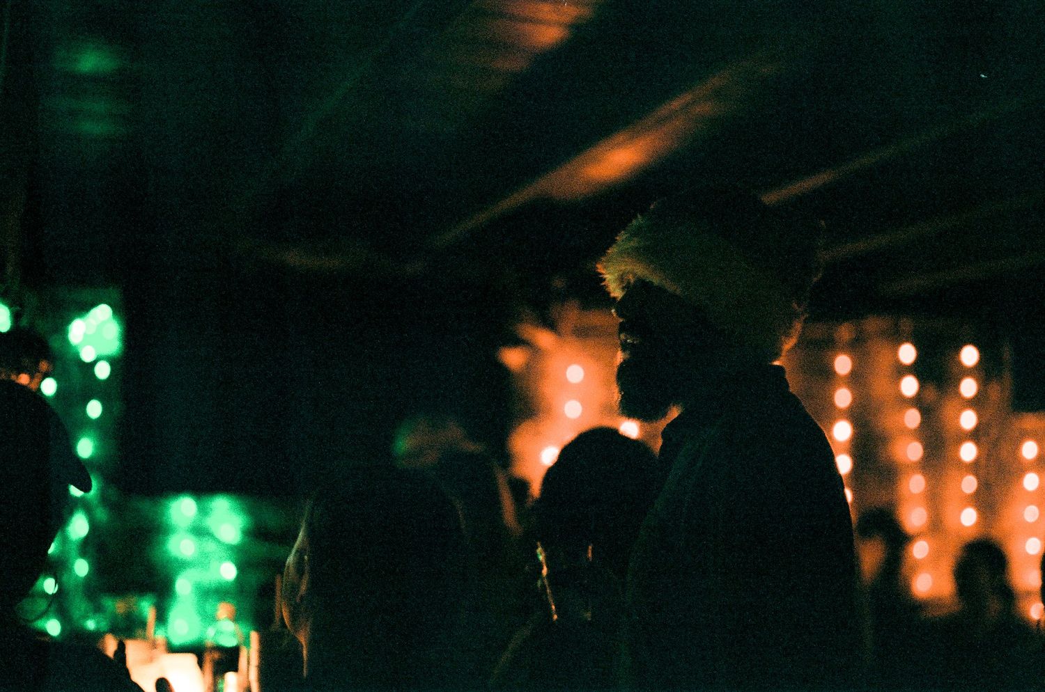 Silhouetted figures in a dark room illuminated by green and orange ambient lighting.