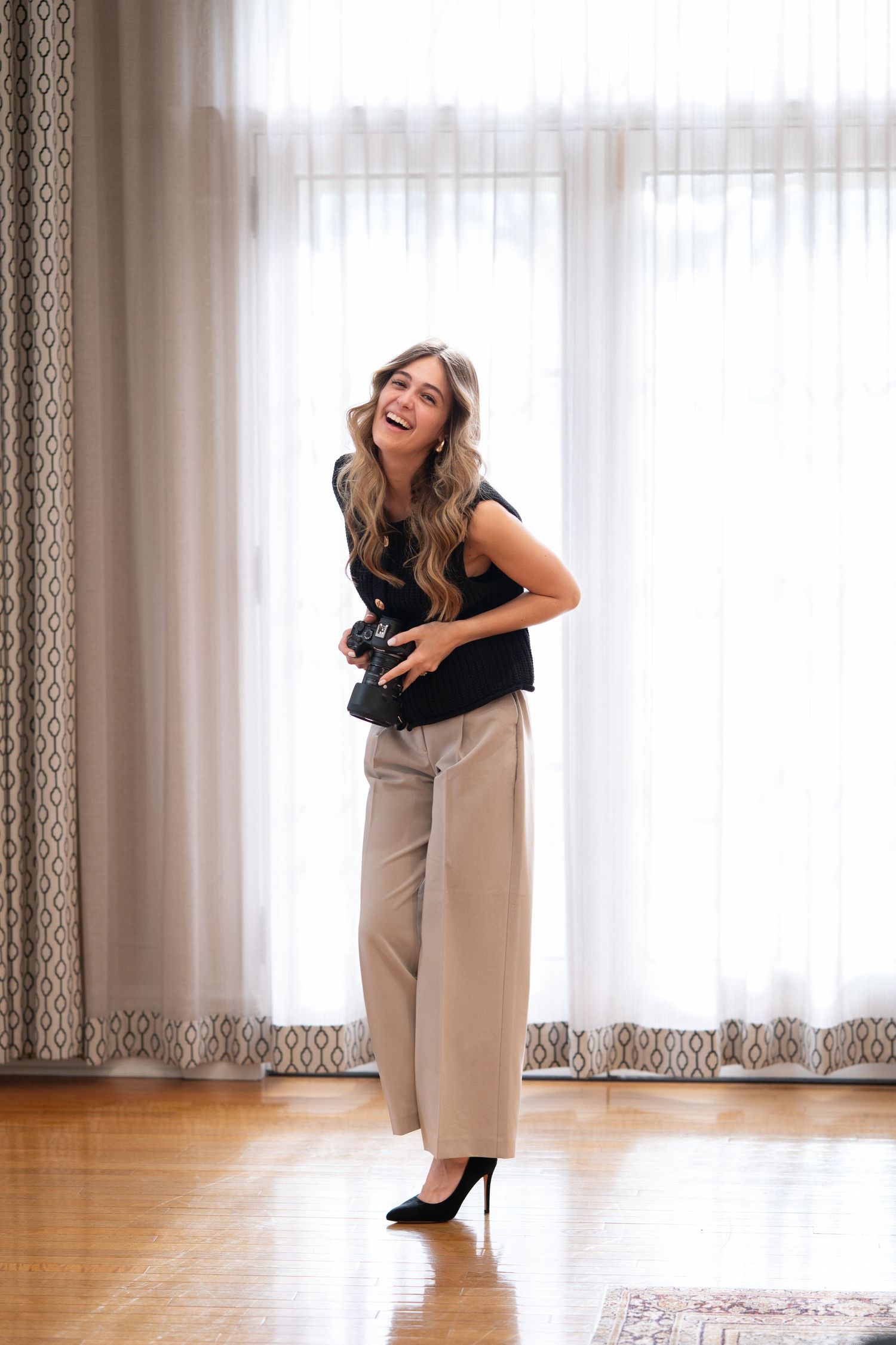 Stylish portrait session in an elegant room with hardwood floors and sheer curtains.