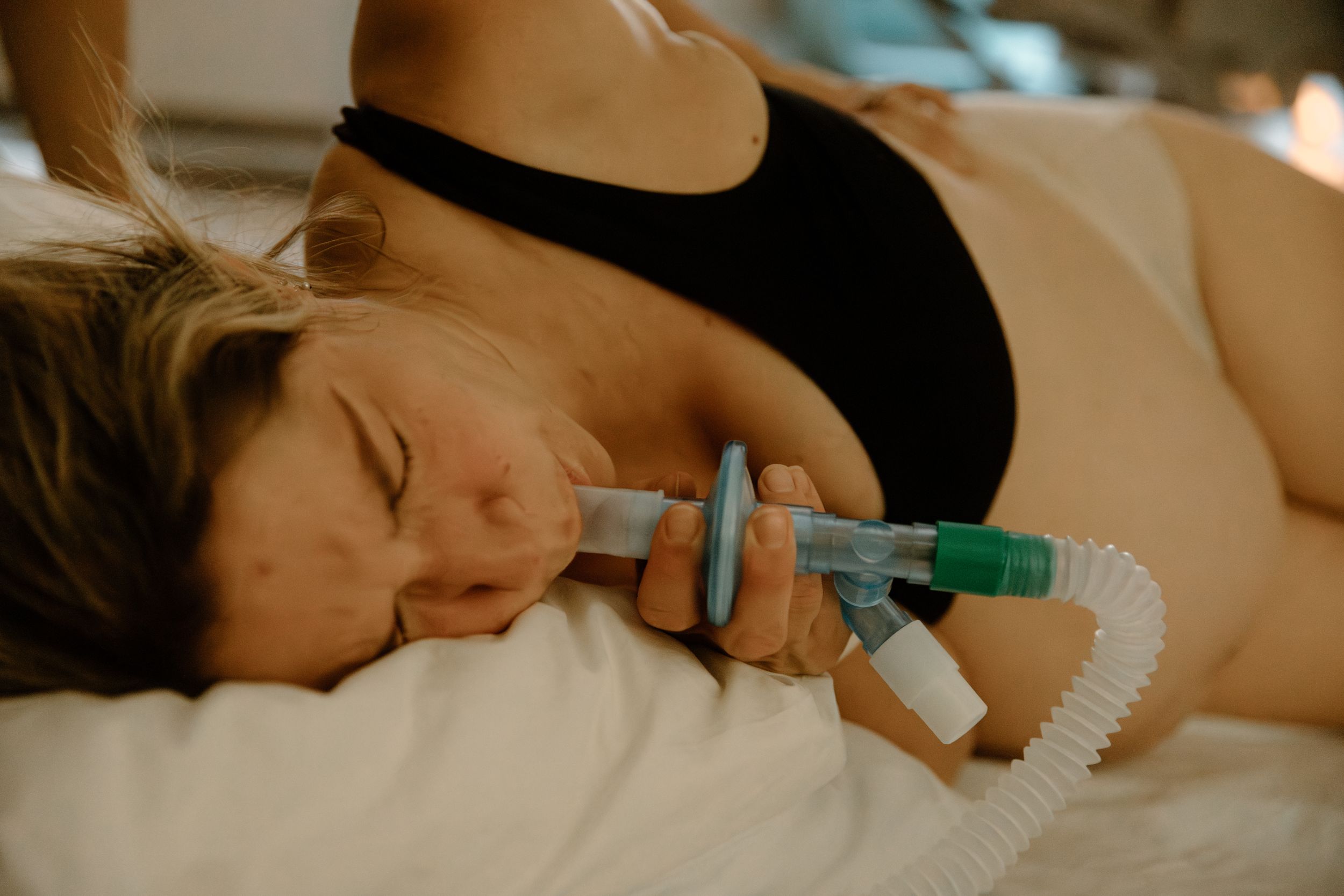 A mother in labour, takes some gas to help with the pain during a birth photoshoot, in Karratha, WA