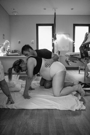 A mother is on all fours while her partner supports her in Karratha. Birth photoshoot