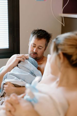A father holds his newborn baby in a hospital room during a birth photography session in Karratha, WA