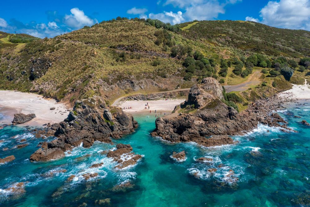 Aerial panoramic view of rugged coastal cliffs and turquoise waters along a scenic tropical shoreline.