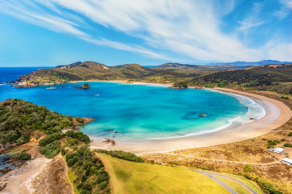 Panoramic view of pristine sandy beaches and turquoise waters along a rugged coastline under bright blue skies.