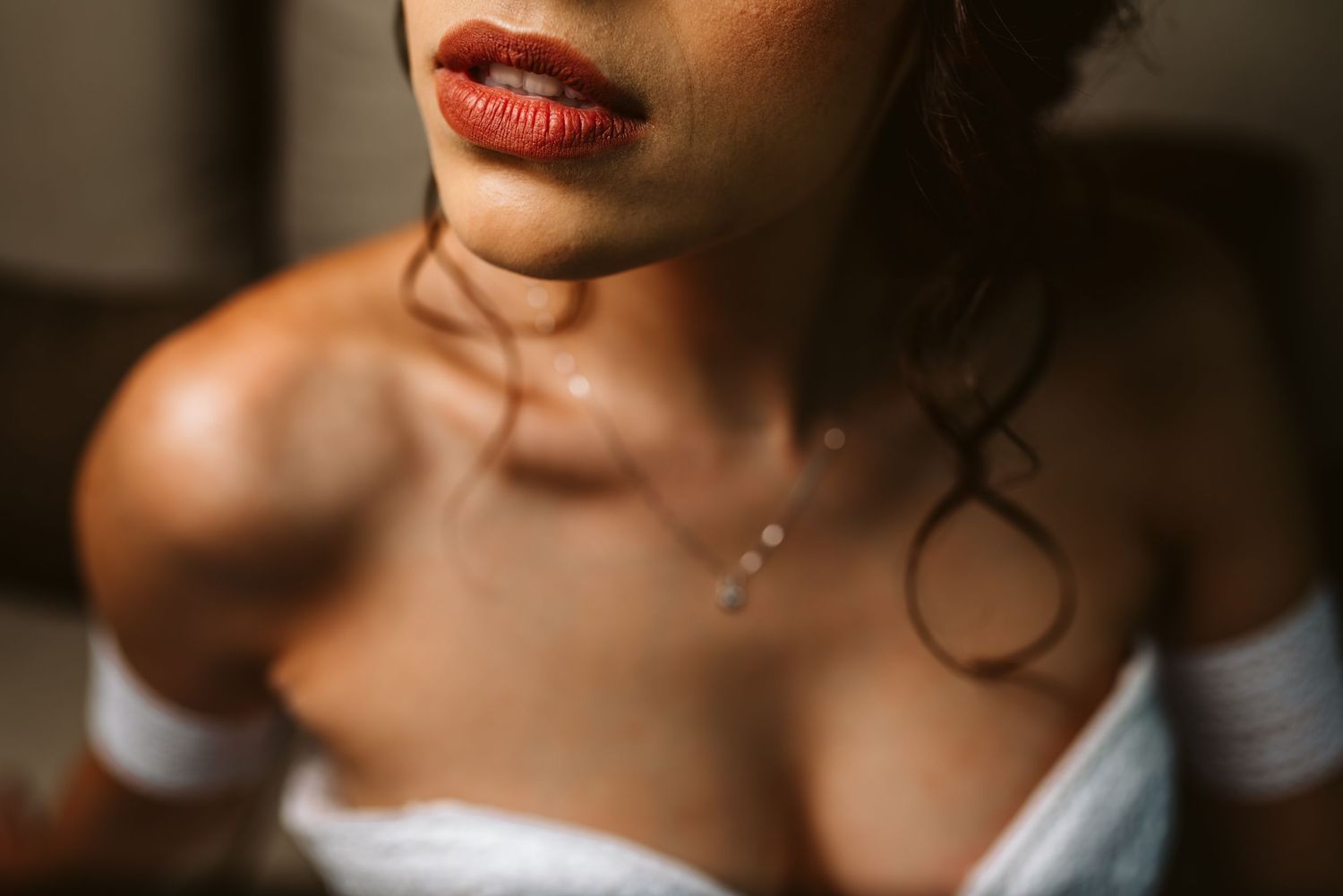 Close-up shot of red lipstick on lips against a dark background.