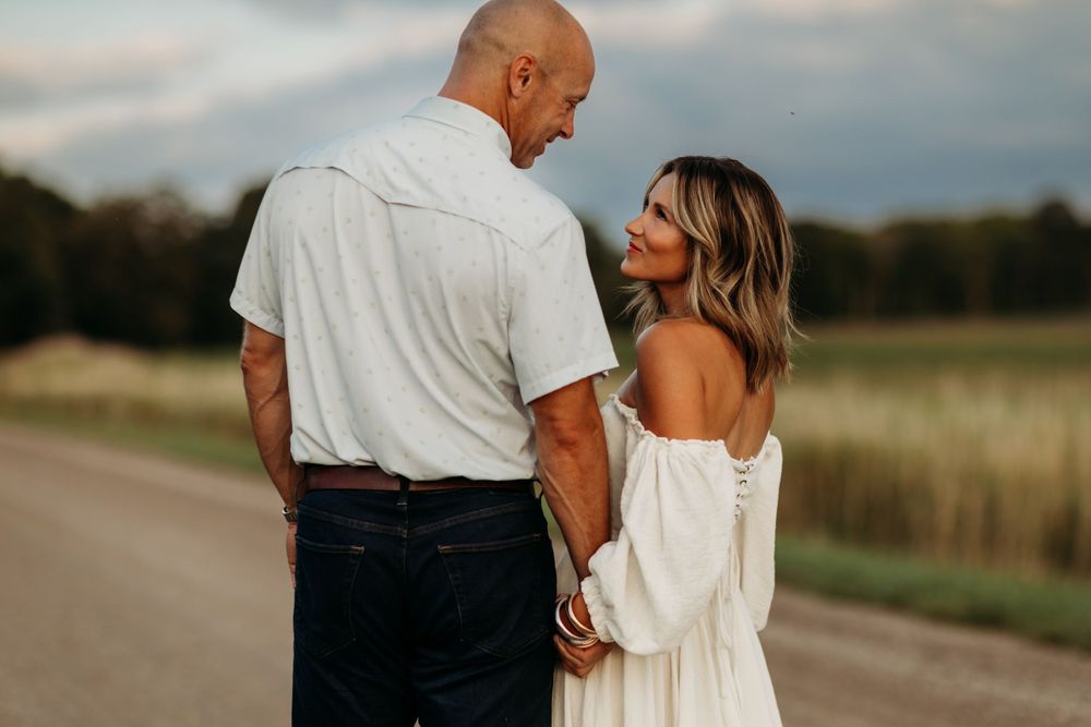 Couple shares an intimate moment on a country road at sunset.