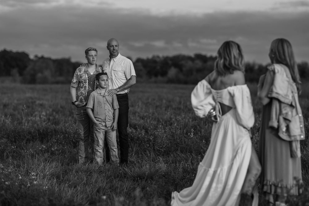 Black and white portrait of a group posing together in an open field at dusk.