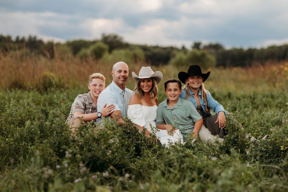 Group photo in a rustic field setting with western style clothing and hats.