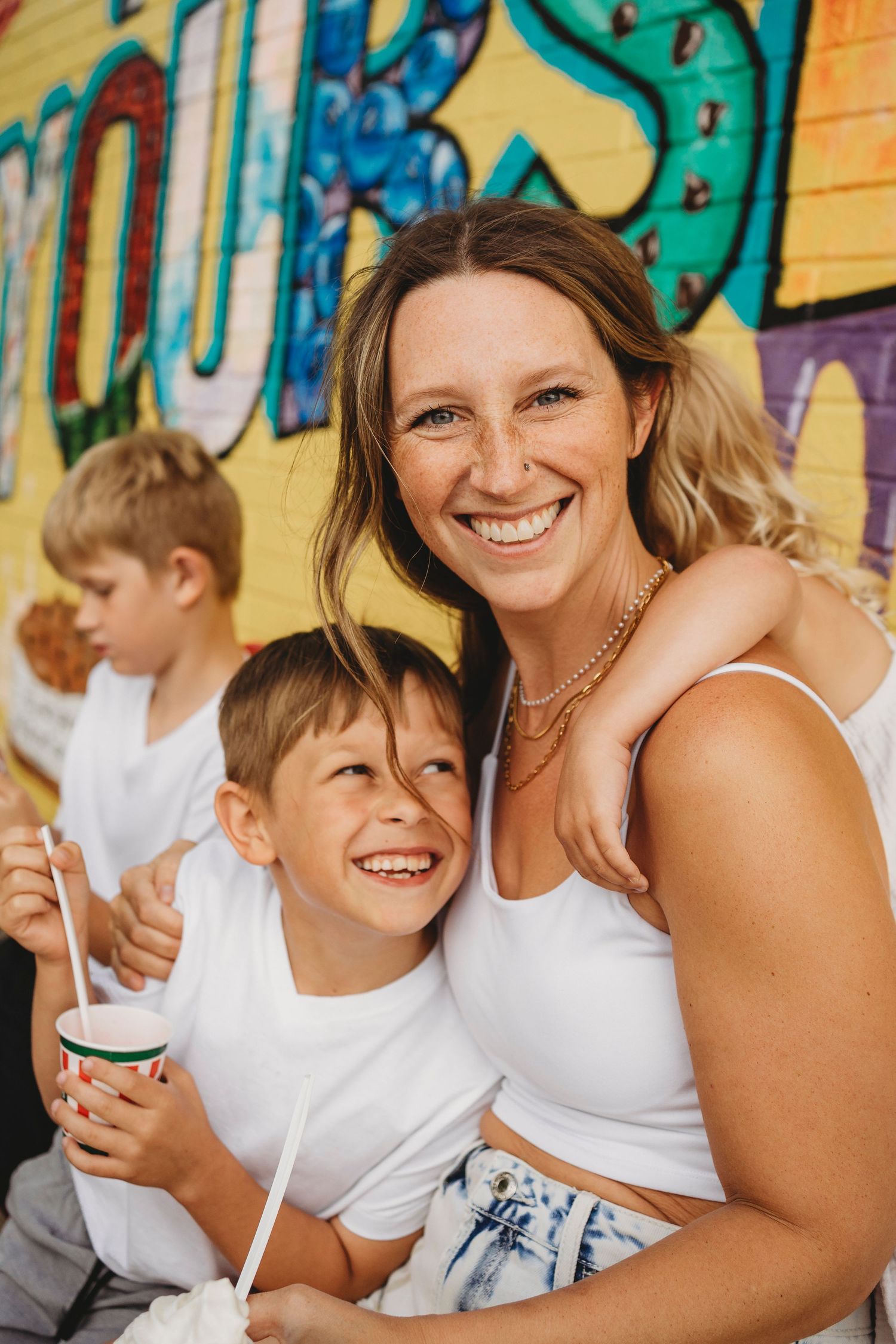 Casual outdoor portrait against vibrant street art mural in summer.
