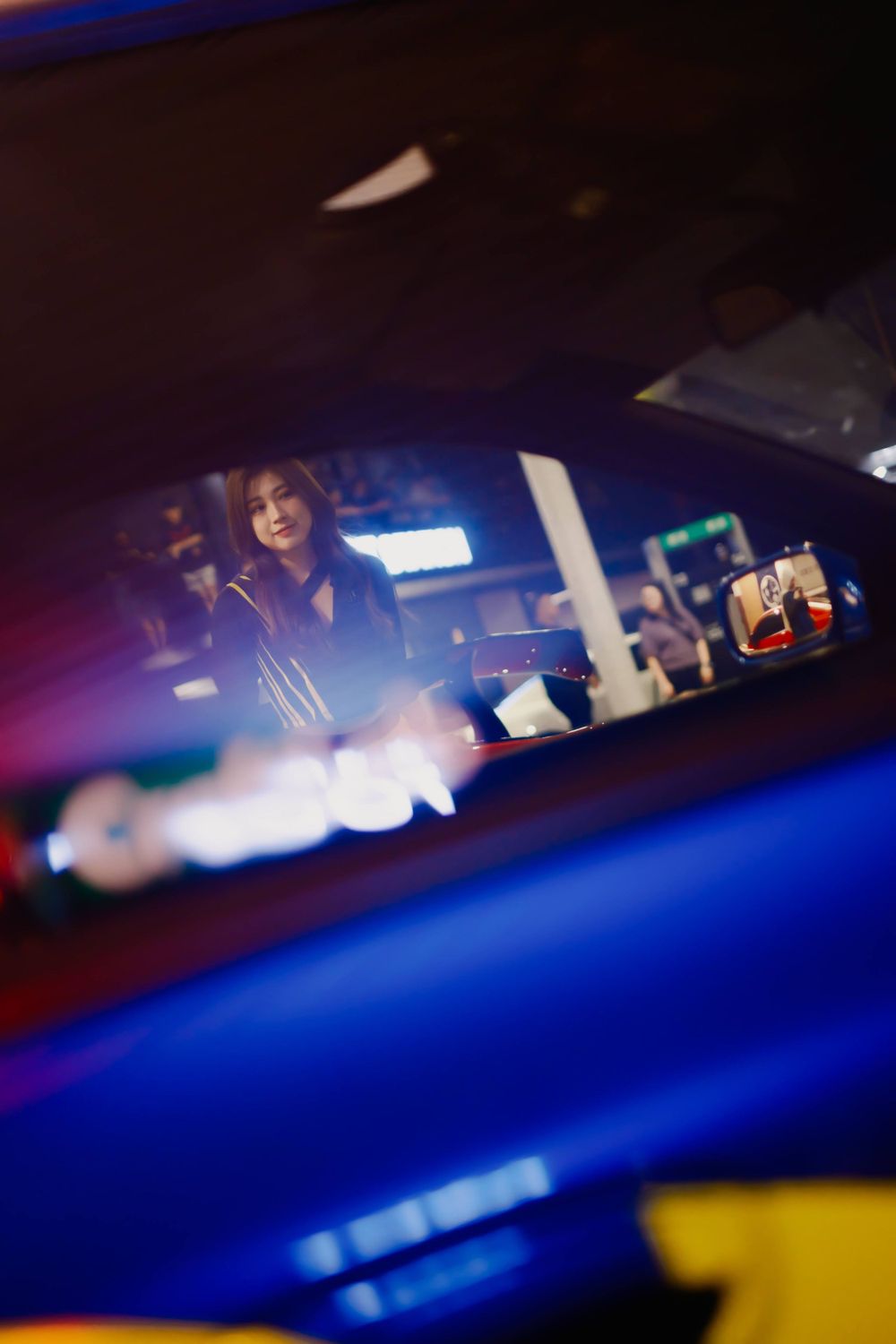 Interior shot of car rearview mirror at night with reflections and blue lighting.