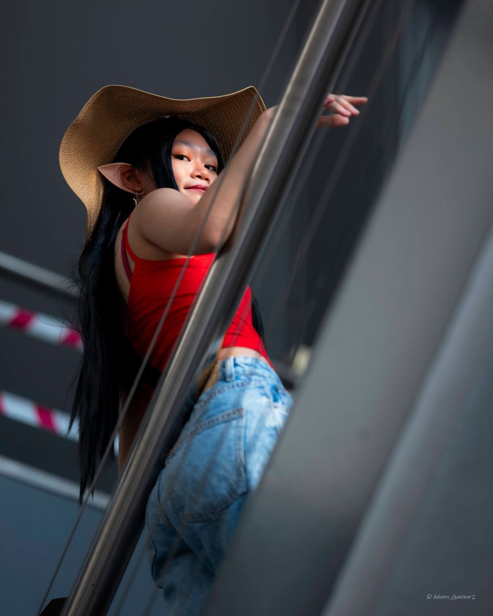 A stylish portrait of someone in a wide-brimmed hat peering around a corner.