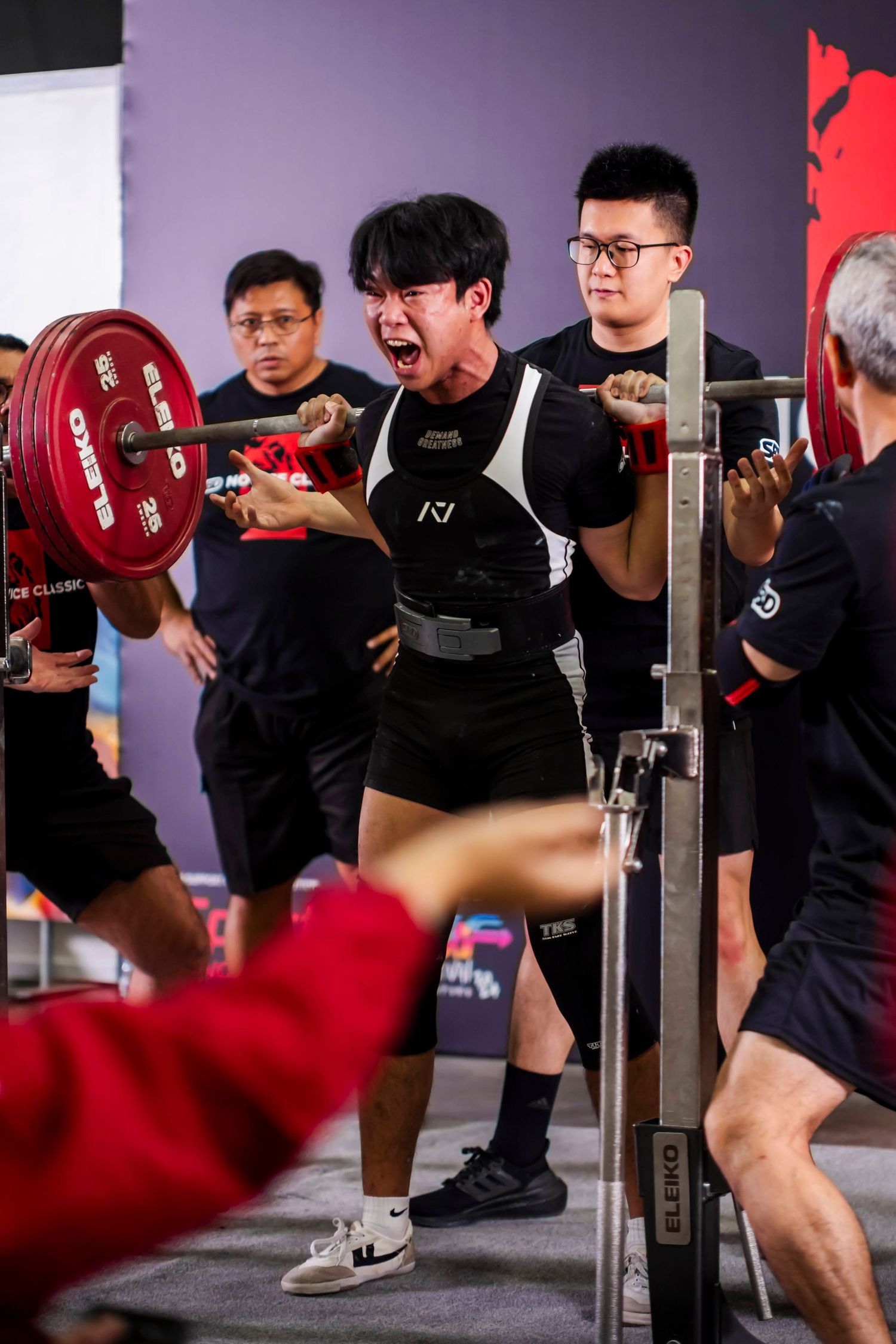 Weightlifter performing a squat with red plates during a competition or training session.