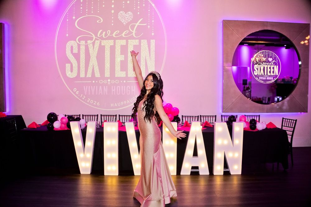 Teen girl poses at Sweet Sixteen party for Vivian, surrounded by large letter lights and pink decorations.