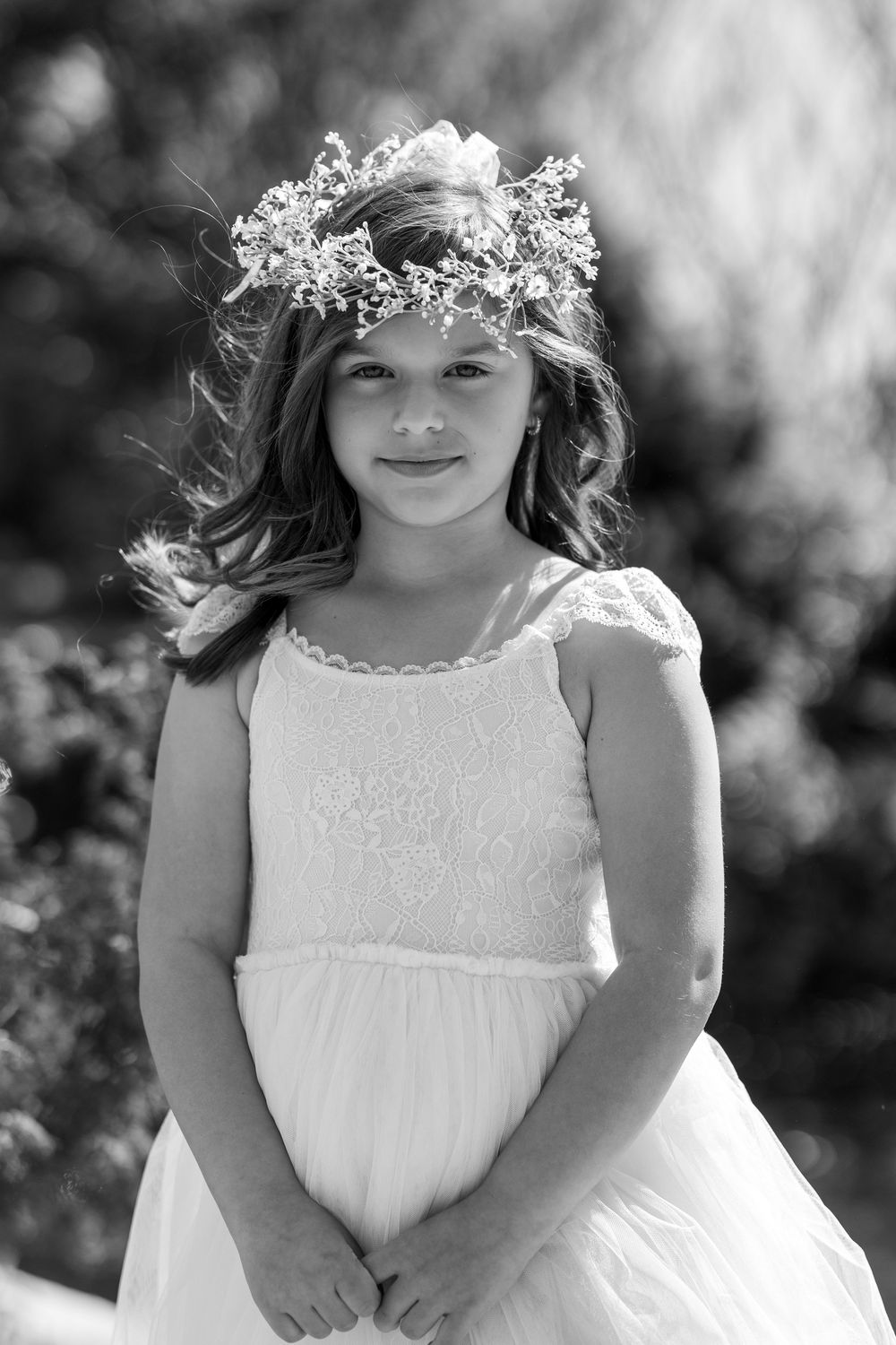 A black and white photo series showing the flower girl in a white dress and floral crown in an outdoor setting with natural lighting.
