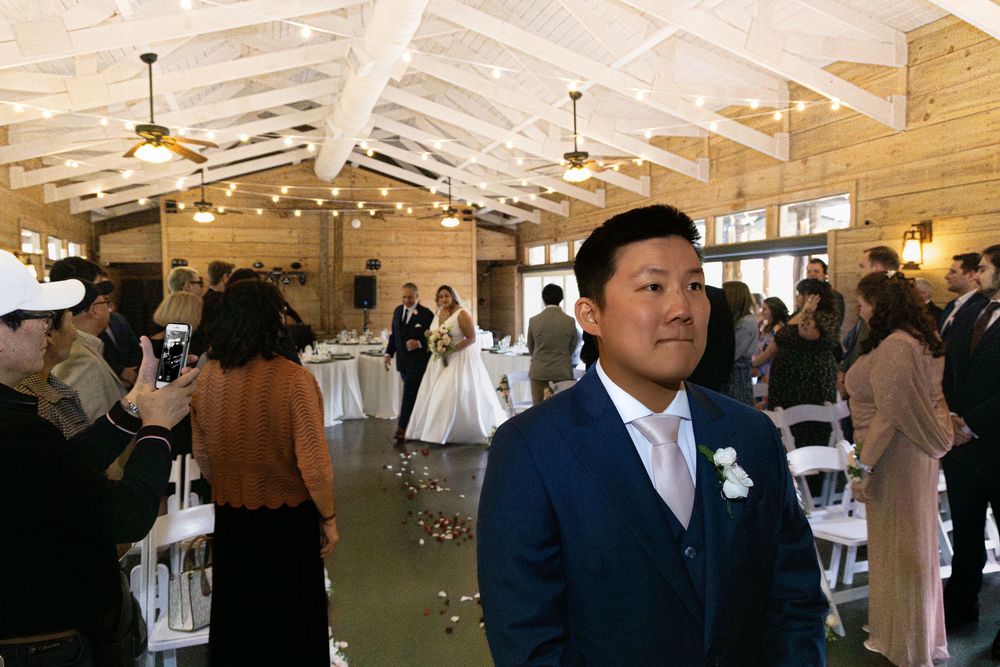 Entrance of the bride with the groom in the foreground and his back is turned.