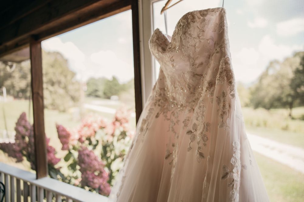 A collection of elegant blush pink wedding dresses hanging on display in a bridal boutique.