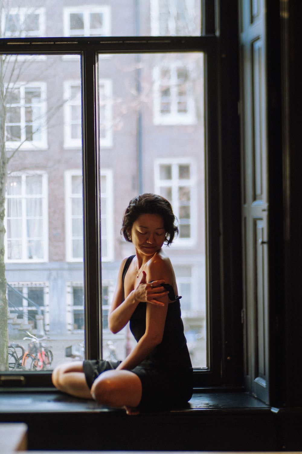 A silhouetted figure sits contemplatively by a window in dramatic lighting.