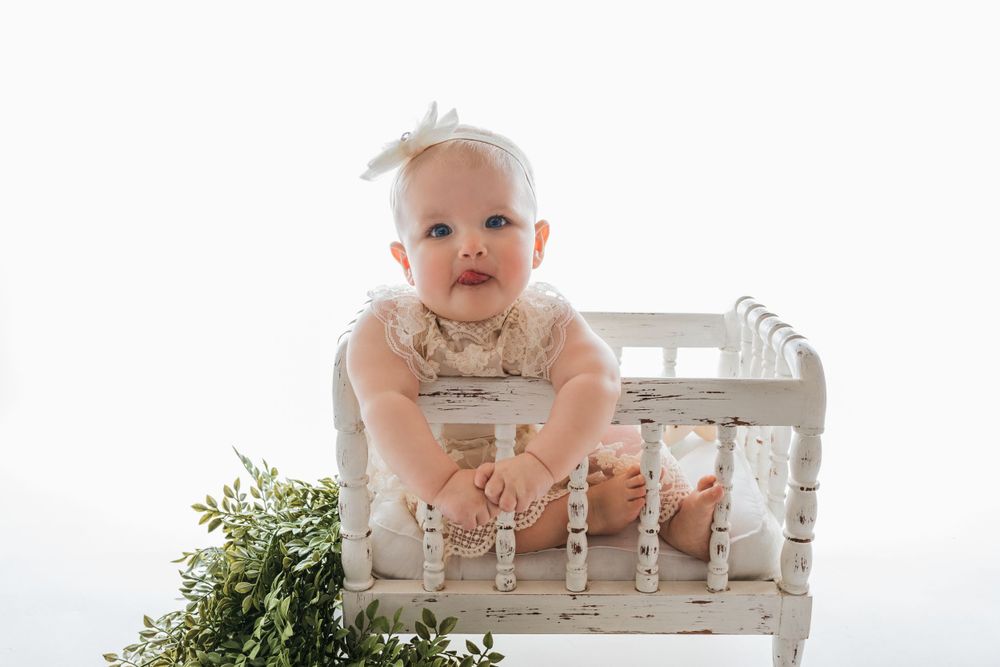 Cedar park TX photography milestone session, baby girl in white crib, lace cream dress and bow in her hair, backlit