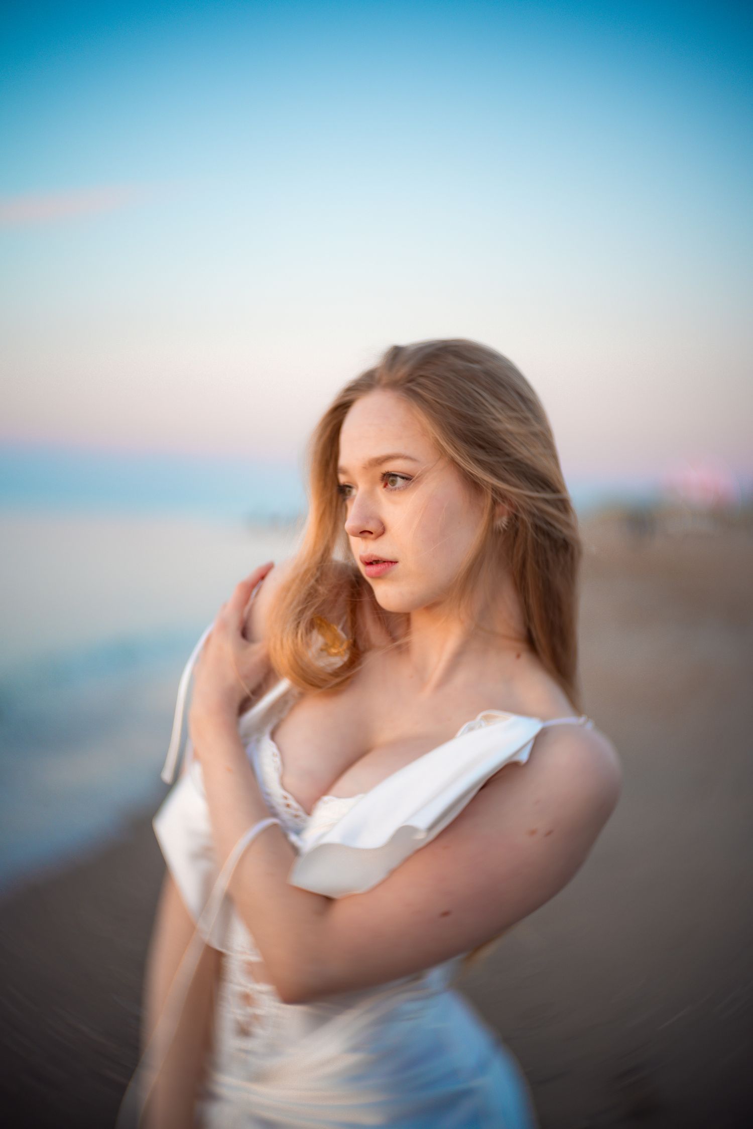 Dreamy portrait at sunset with soft lighting and pastel sky colors reflecting off the beach. Shot with Petzval lens