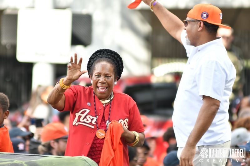 Sports fans in red and orange attire cheering enthusiastically at an outdoor event.