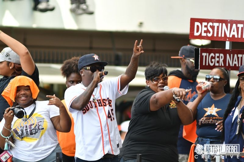 Crowd of sports fans celebrating and making peace signs at an outdoor event.