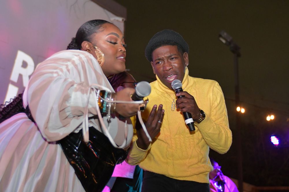 Two performers share a microphone while entertaining on stage.