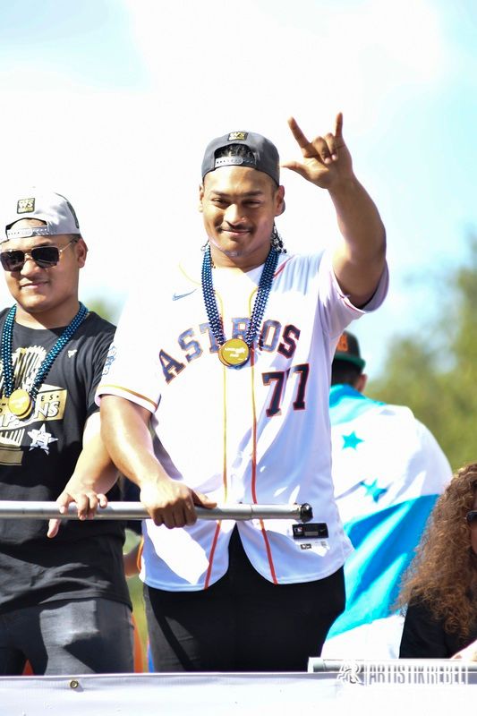 Fan wearing Astros jersey number 77 making peace sign during celebration.