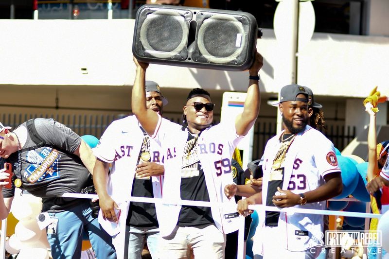 Astros players hold up a large boombox speaker during championship parade celebrations.