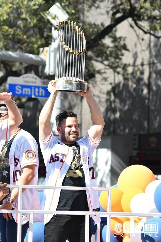 Player raises World Series trophy during championship parade celebration.