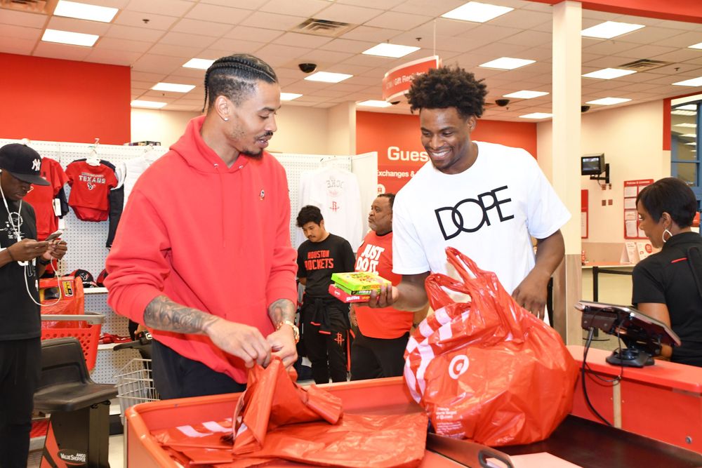 People helping pack red shopping bags at Target store checkout counter.