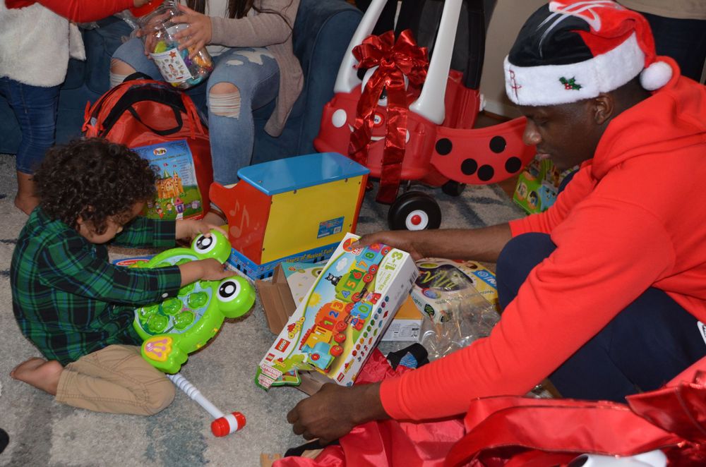 People handling toys and gifts during holiday charity event.