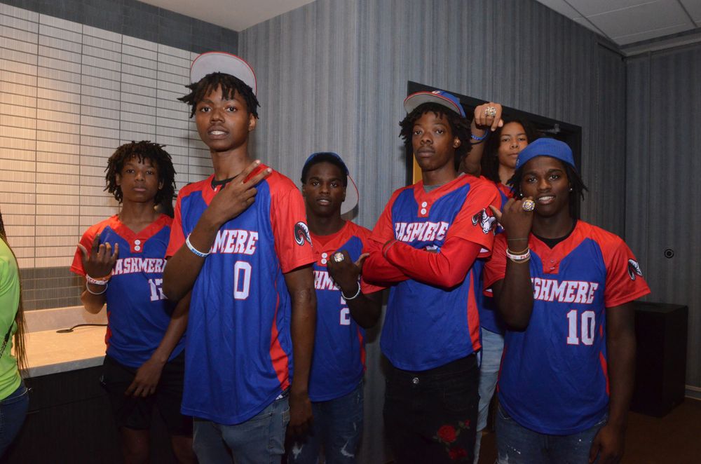 Baseball players wearing blue and red jerseys pose together during team event.